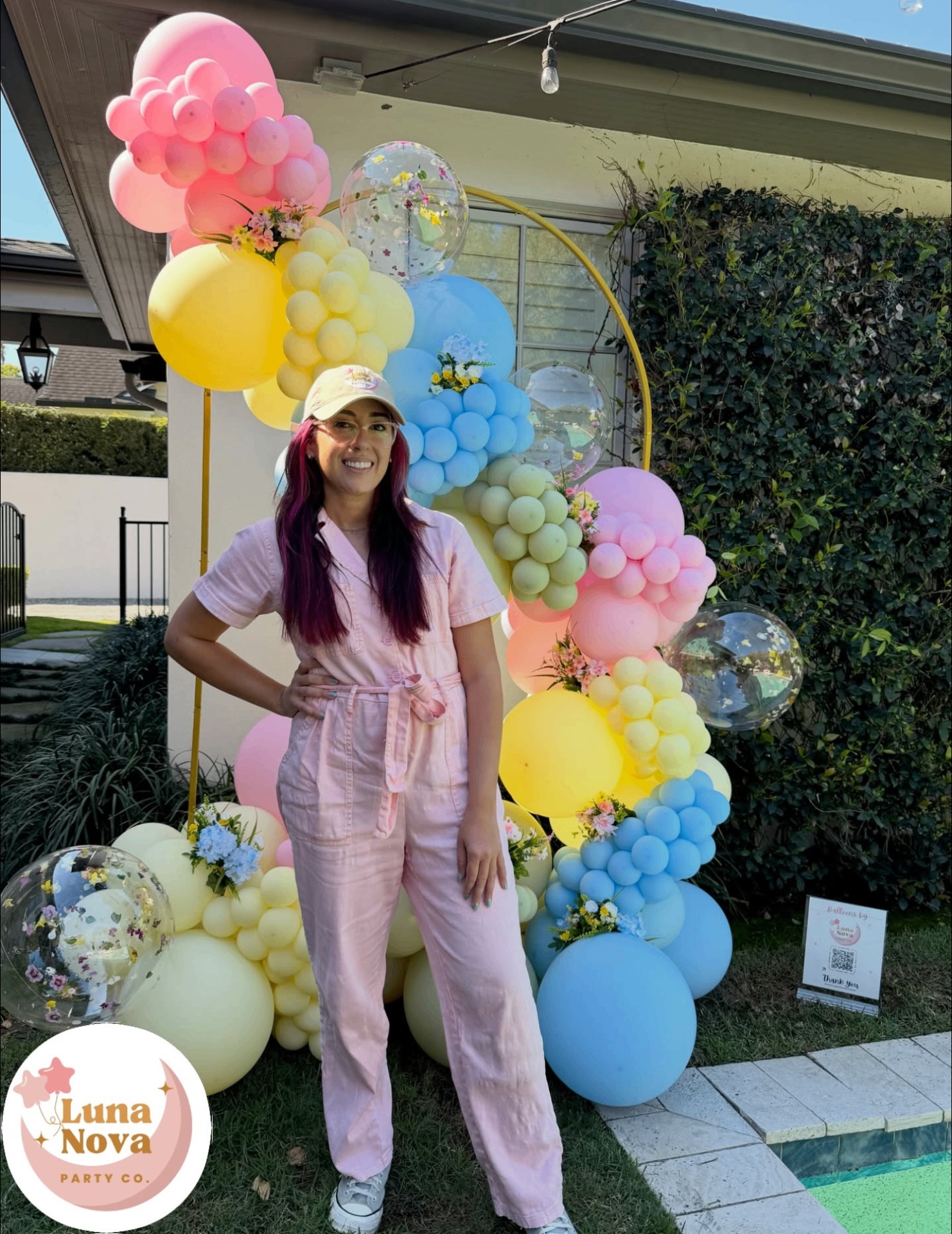 Judy, owner of Luna Nova Party Co., standing in front of a colorful balloon installation
